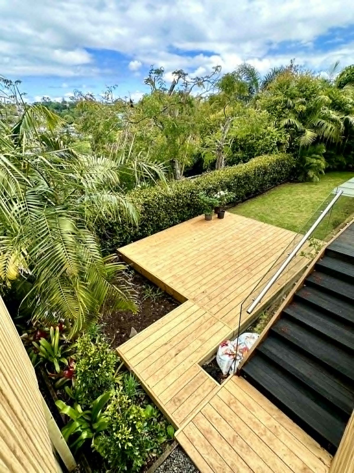 Elevated timber deck with glass balustrade overlooking native bush in Swanson